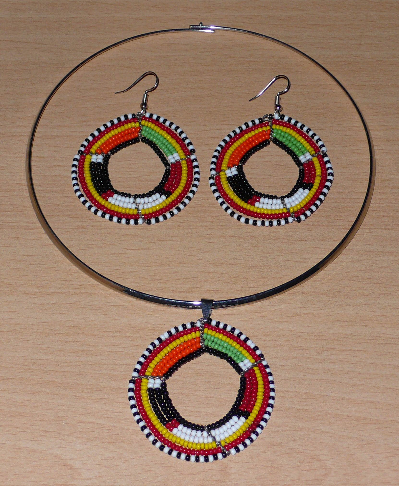 Parure moderne de bijoux africains Massai se composant d'un ras-de-cou en laiton argenté orné d'un pendentif rond en perles de verre noires et multicolores, et d'une paire de boucles d'oreilles assorties. Timeless Fineries