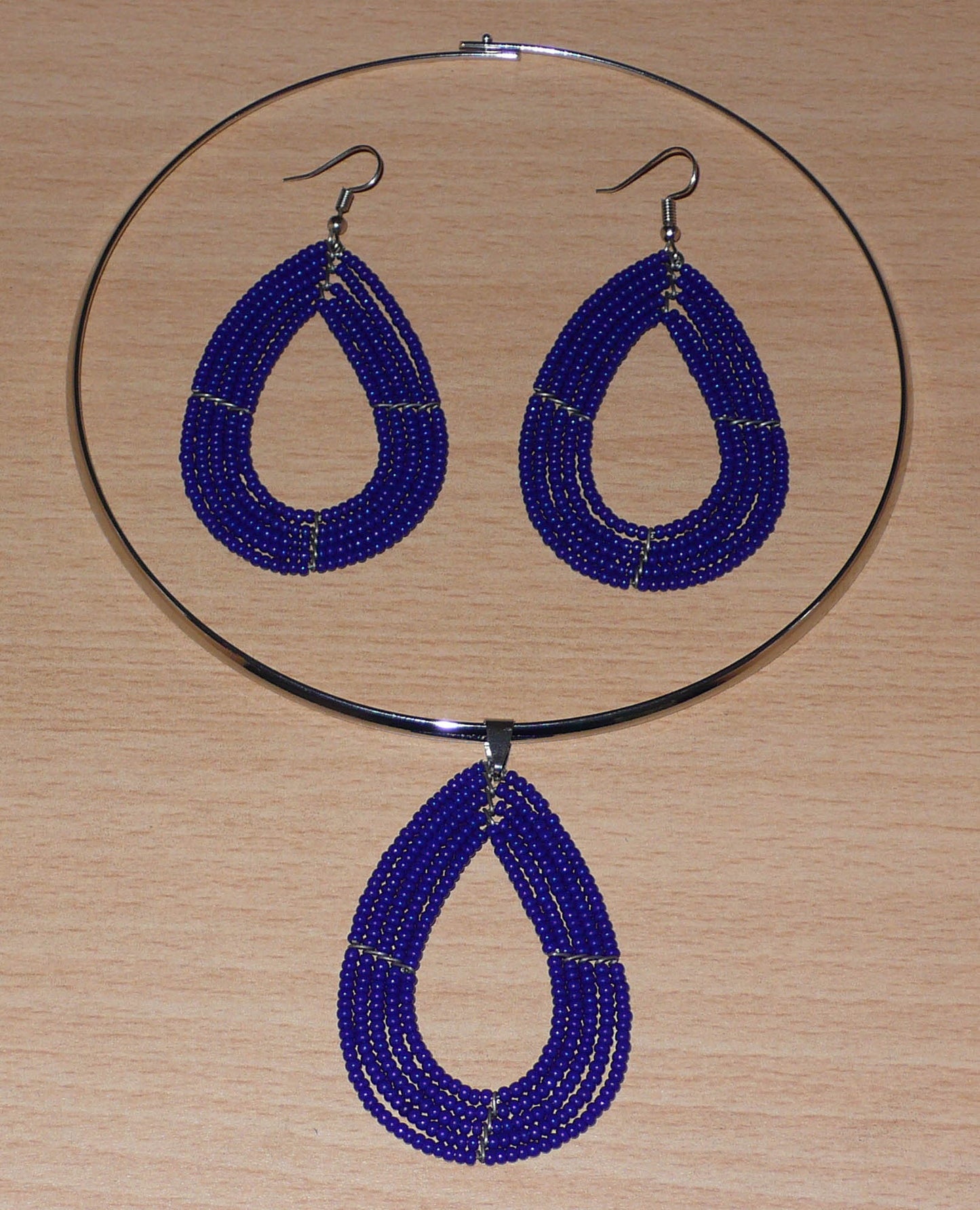 Parure contemporaine très chic de bijoux Massai comprenant un collier ras-de-cou en laiton argenté agrémenté d'un pendentif en forme de goutte fait de perles de rocaille bleu marine, ainsi qu'une paire de boucles d'oreilles assorties. Timeless Fineries